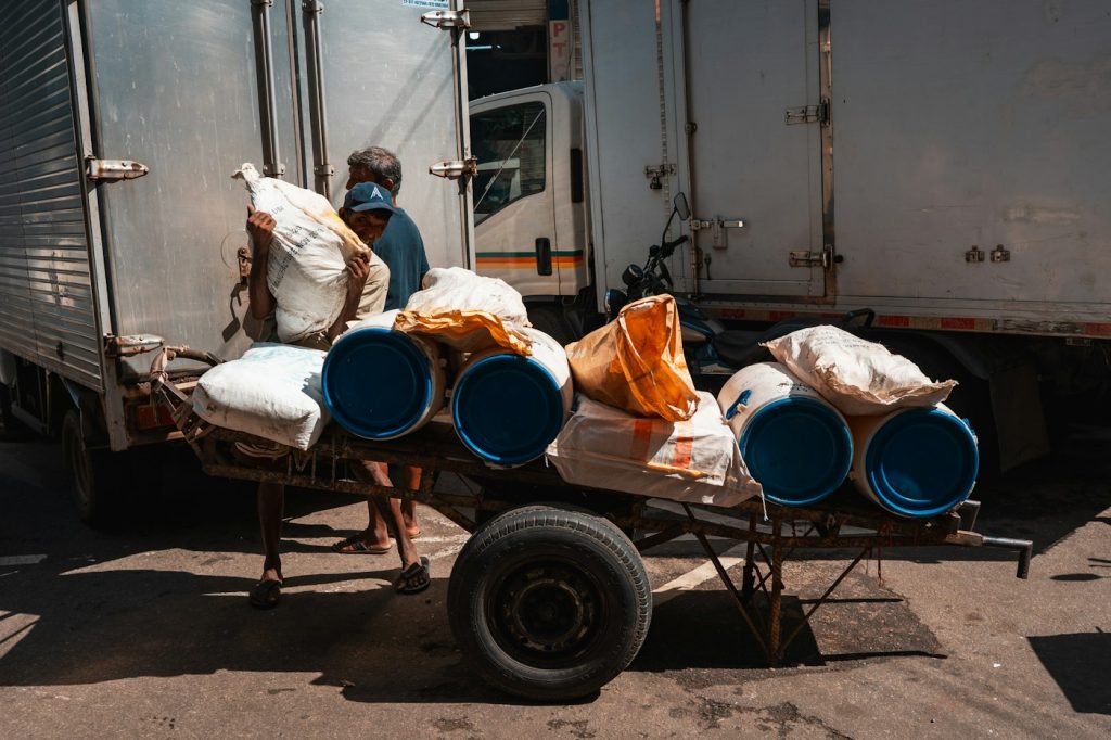 Blue barrels and sacks of goods being loaded for transport