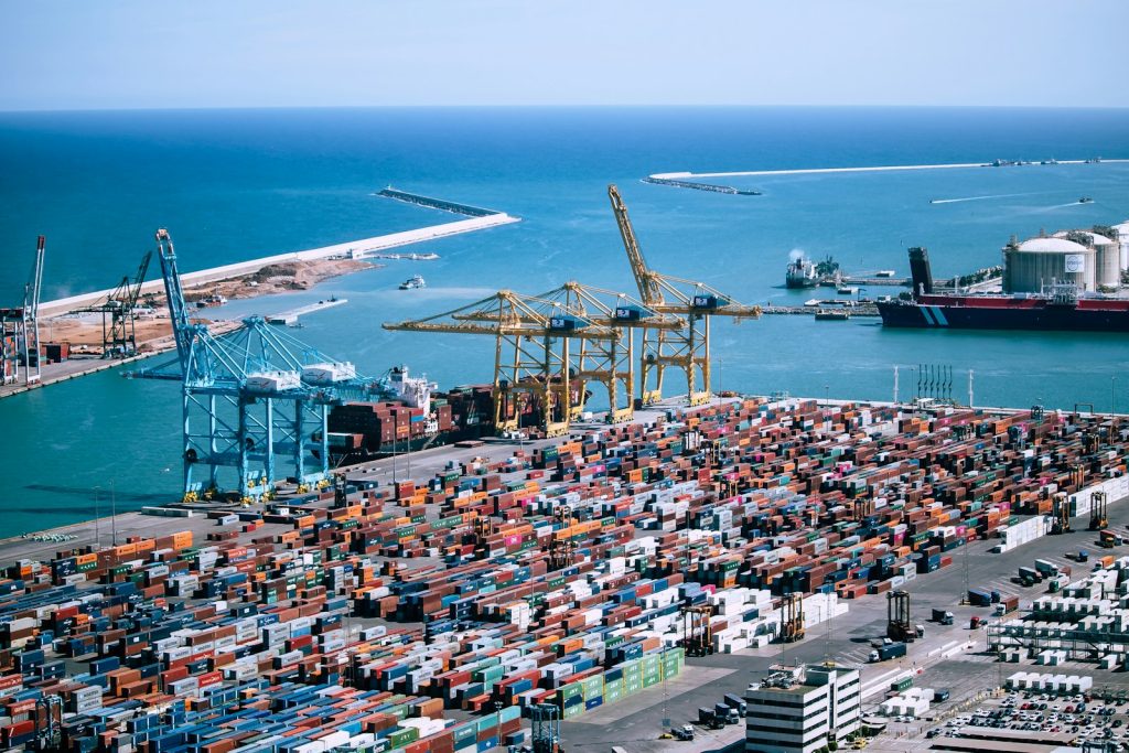 Aerial view of a container port with gantry cranes, stacked shipping containers and a ship at berth